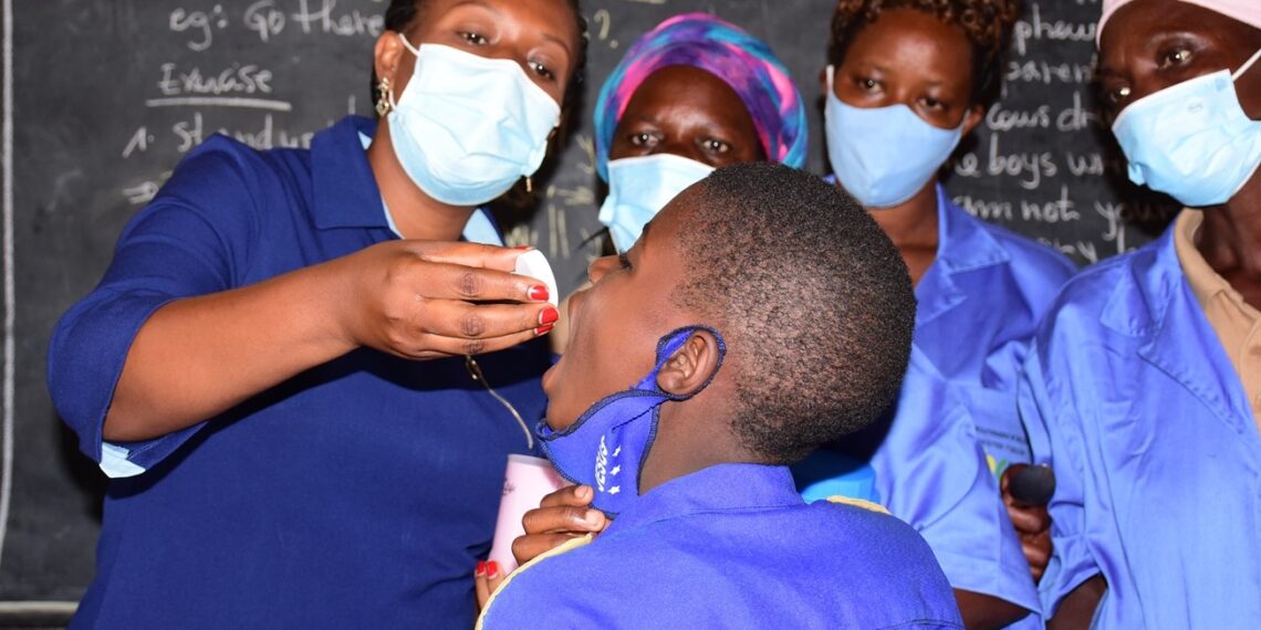 Umuyobozi w'Akarere ka Rwamagana wungirije ushinzwe imibereho myiza y'abaturage, Umutoni Jeanne, aha ikinini umwana ku ishuri rya Ecole Primaire Rwamagana Catholique
