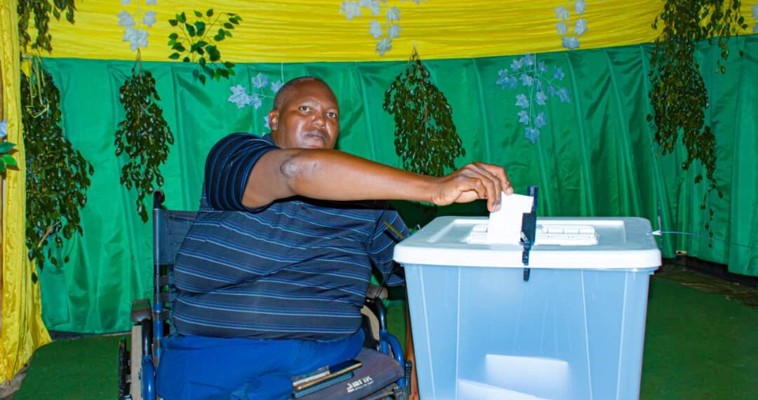 Umwe mu bafite ubumuga wo mu Karere ka Ngoma ashyira urupapuro rw'itora ahabigenewe